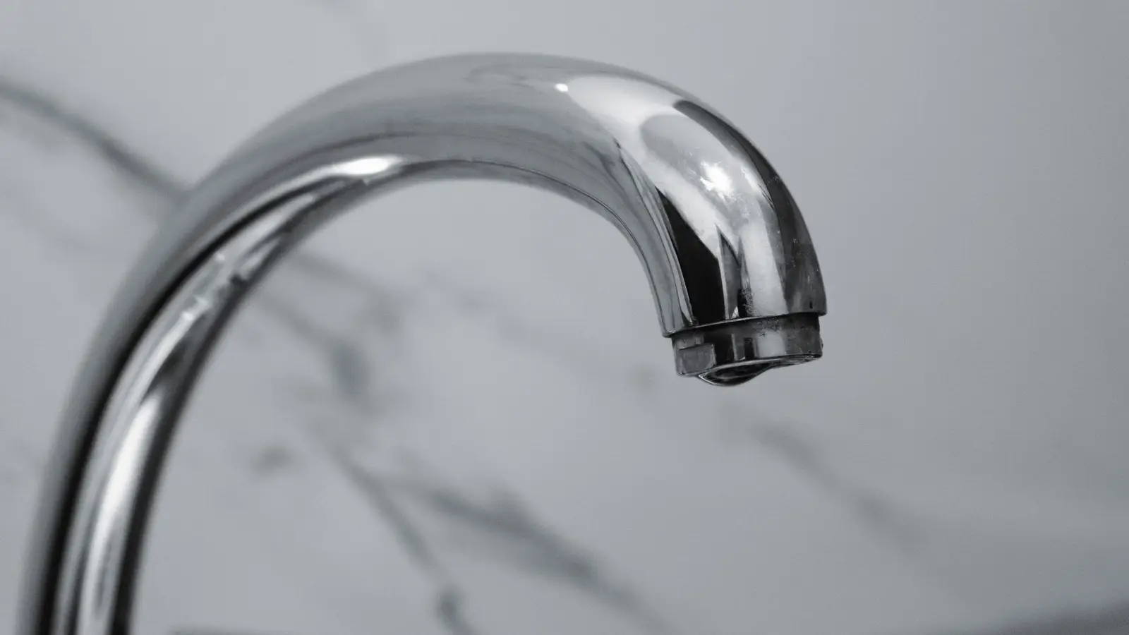 A close-up of a small bathroom faucet in polished chrome hardware