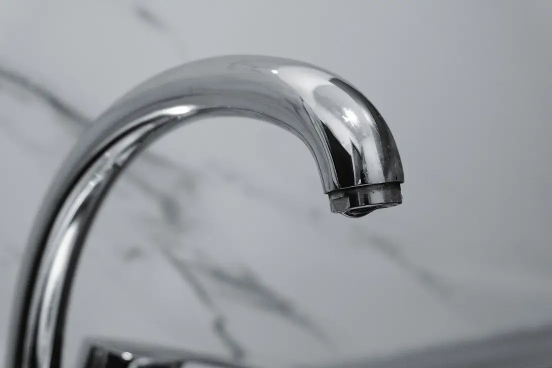 A close-up of a small bathroom faucet in polished chrome hardware