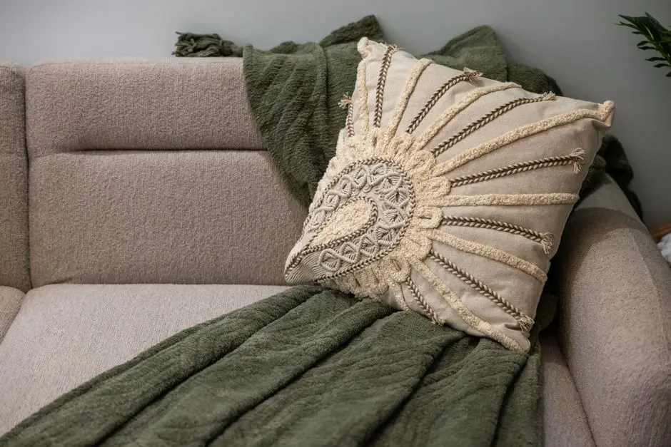 A chunky knit throw and a textured tasseled pillow on a bouclé sofa, an organic modern texture idea