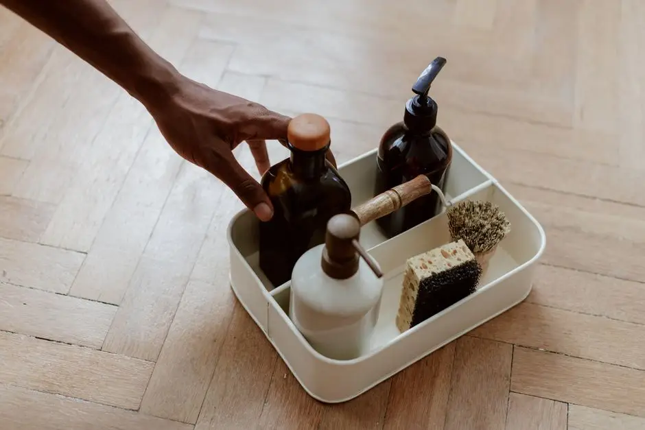 A hand reaching for a cleaning caddy stocked with dish soap, sponge, and scrub brush