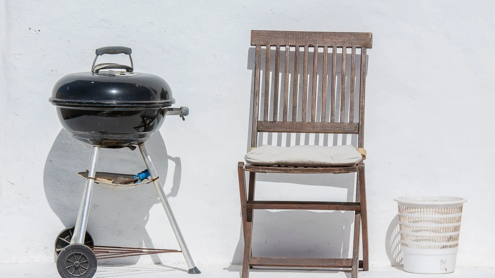 Compact charcoal grill positioned away from the house wall in a backyard BBQ area