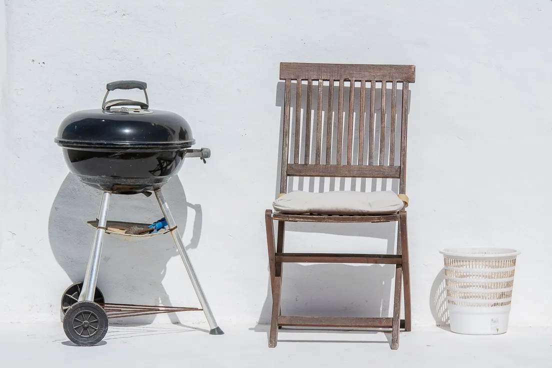 Compact charcoal grill positioned away from the house wall in a backyard BBQ area