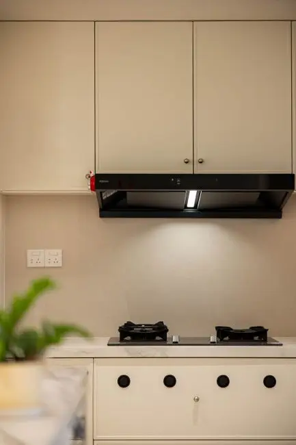 A black range hood mounted over a gas cooktop in a closed kitchen