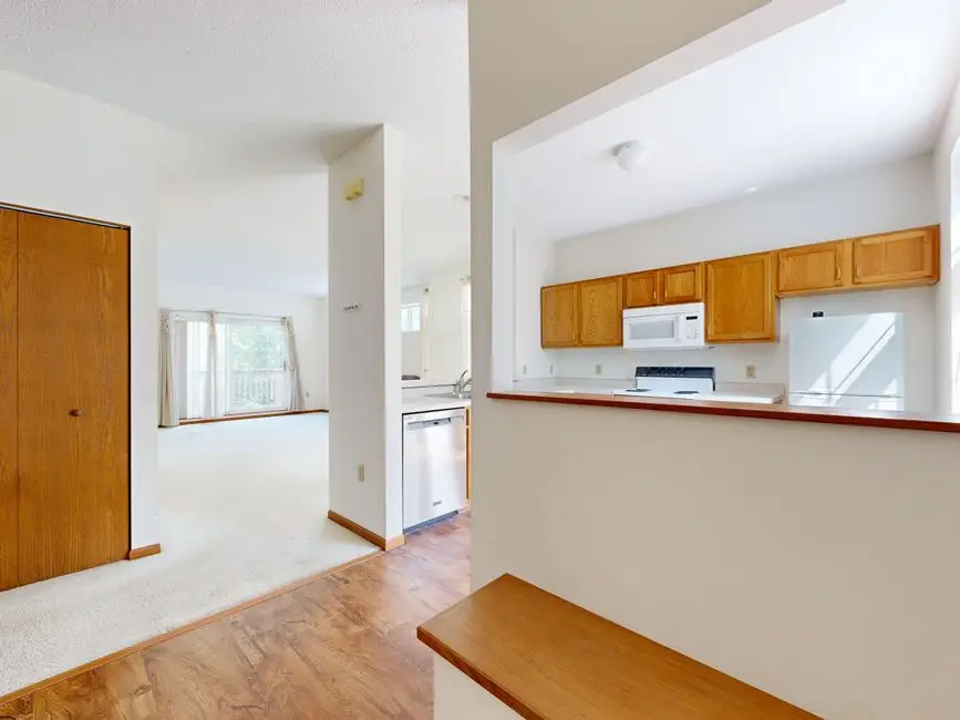 A dated open-plan pass-through kitchen with builder-grade oak cabinets