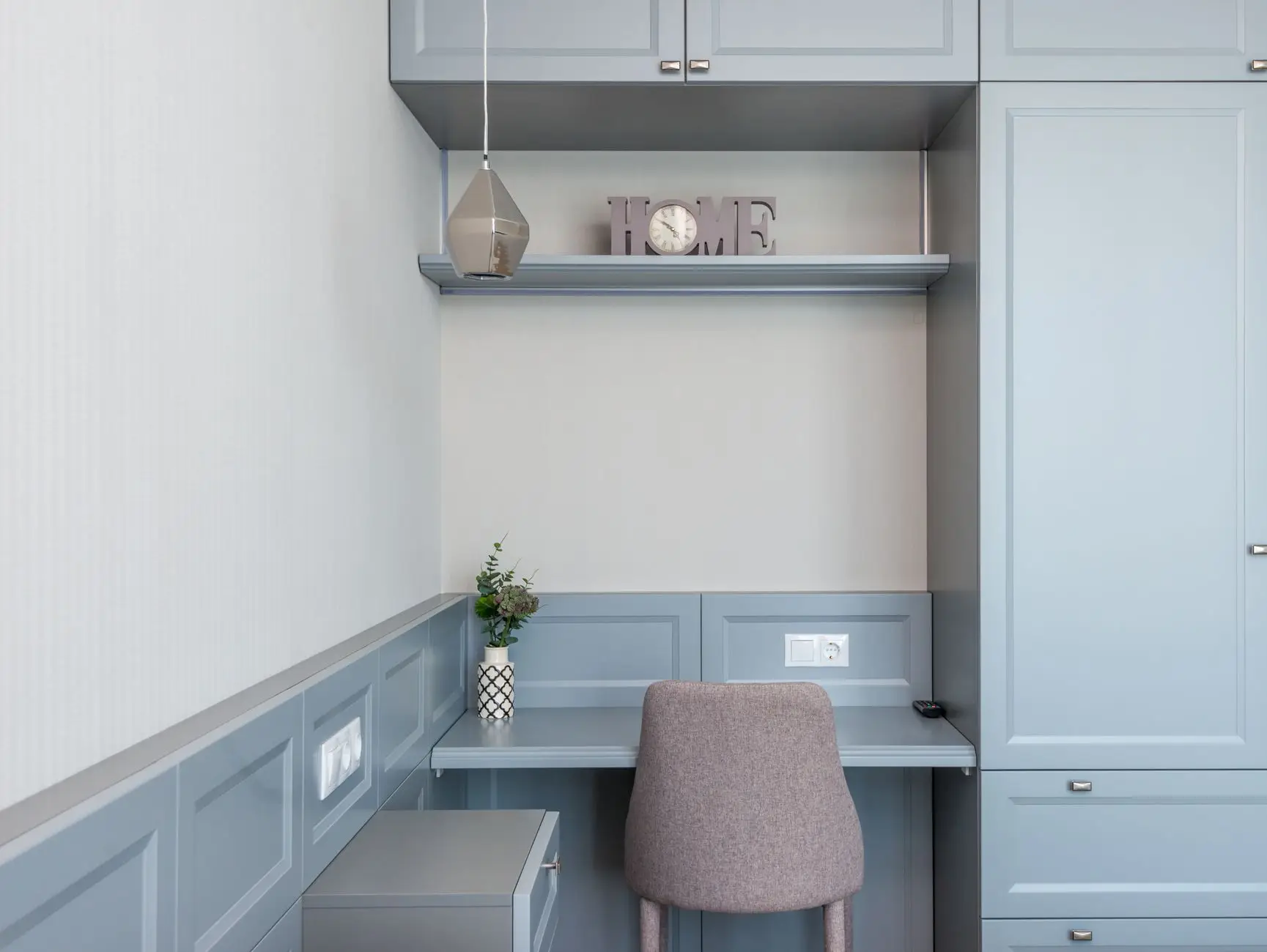 A built-in desk nook with a floating shelf and cabinets on each side, a closet-style office tucked into an alcove