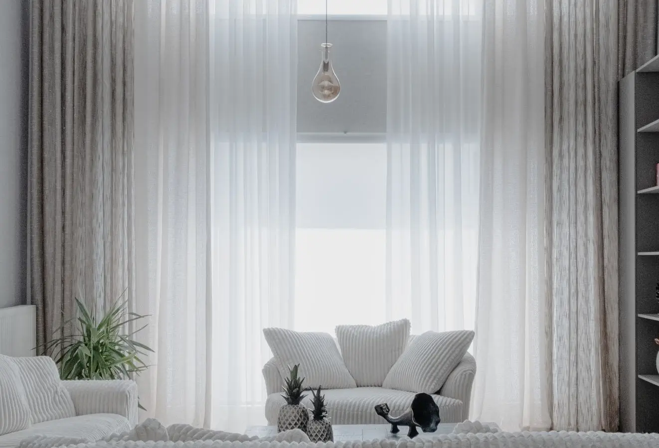 A bright, stark white living room with sheer curtains and pale cloud sofas, an example of cold minimalism
