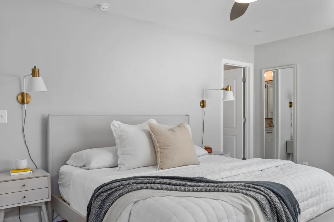 A neutral gray bedroom with cream and beige linen pillows against a plain wall