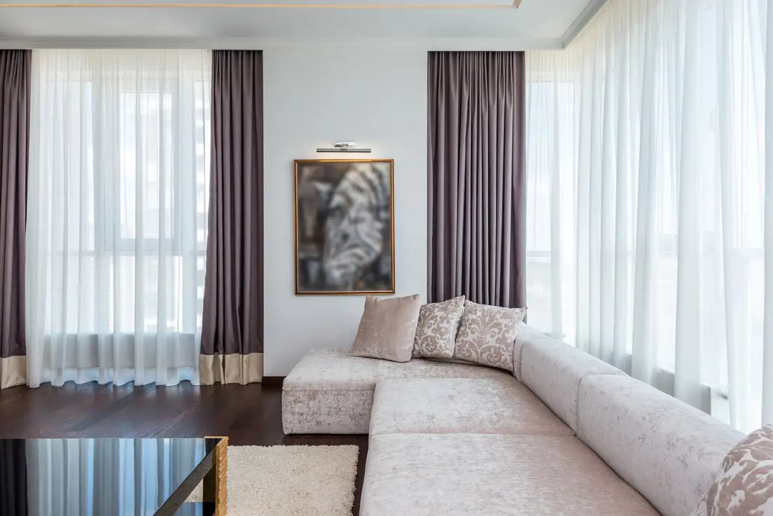 An open small living room with a sectional sofa floating away from large windows