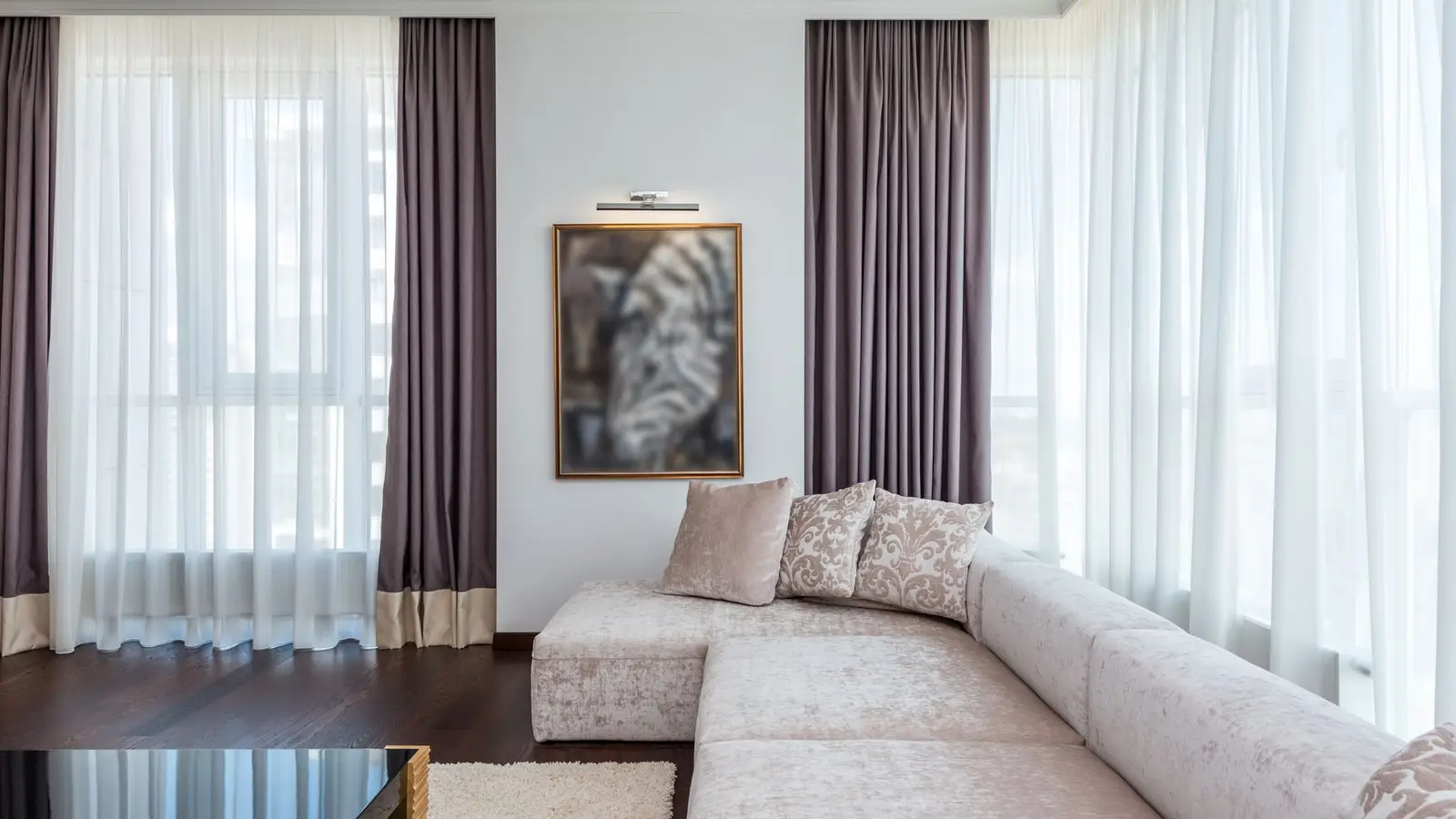 An open small living room with a sectional sofa floating away from large windows