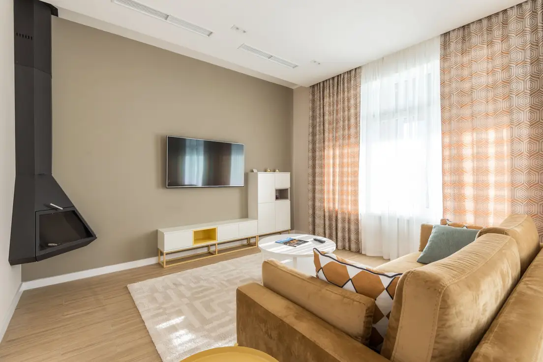A wall-mounted TV positioned off-center on a taupe living room wall above a low white console