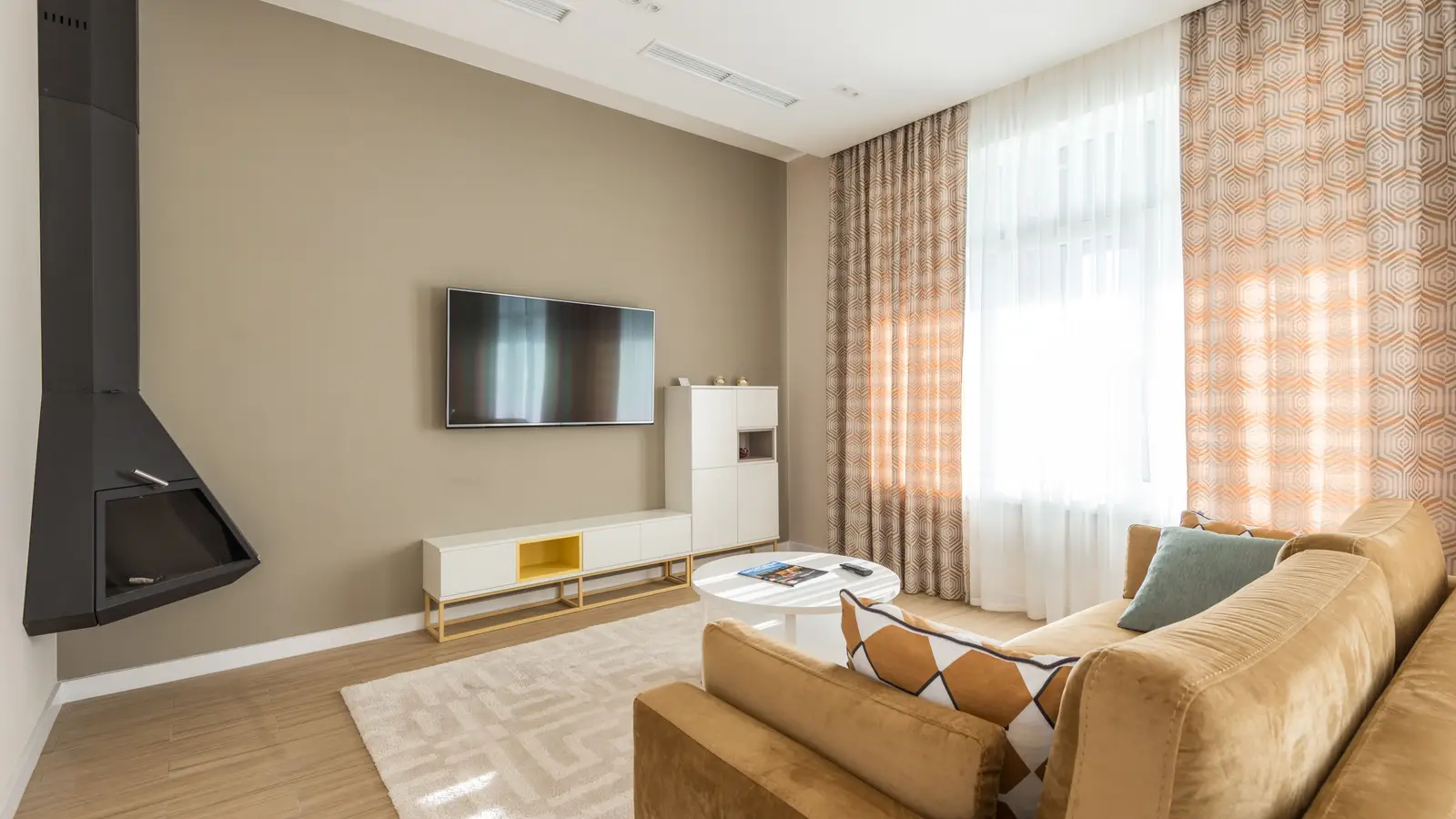 A wall-mounted TV positioned off-center on a taupe living room wall above a low white console