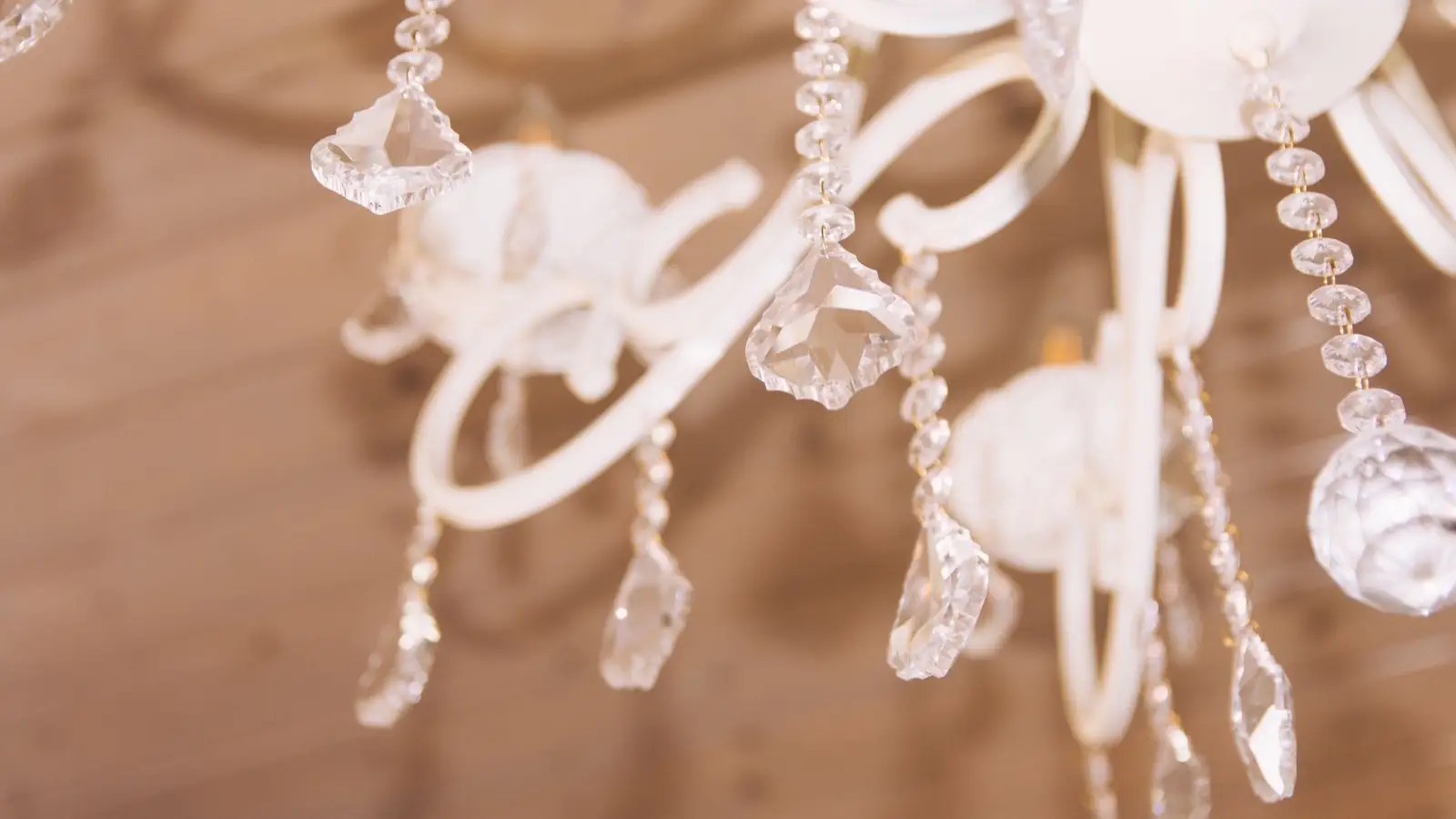 A close-up of crystal drops on a small white chandelier fixture in a bedroom
