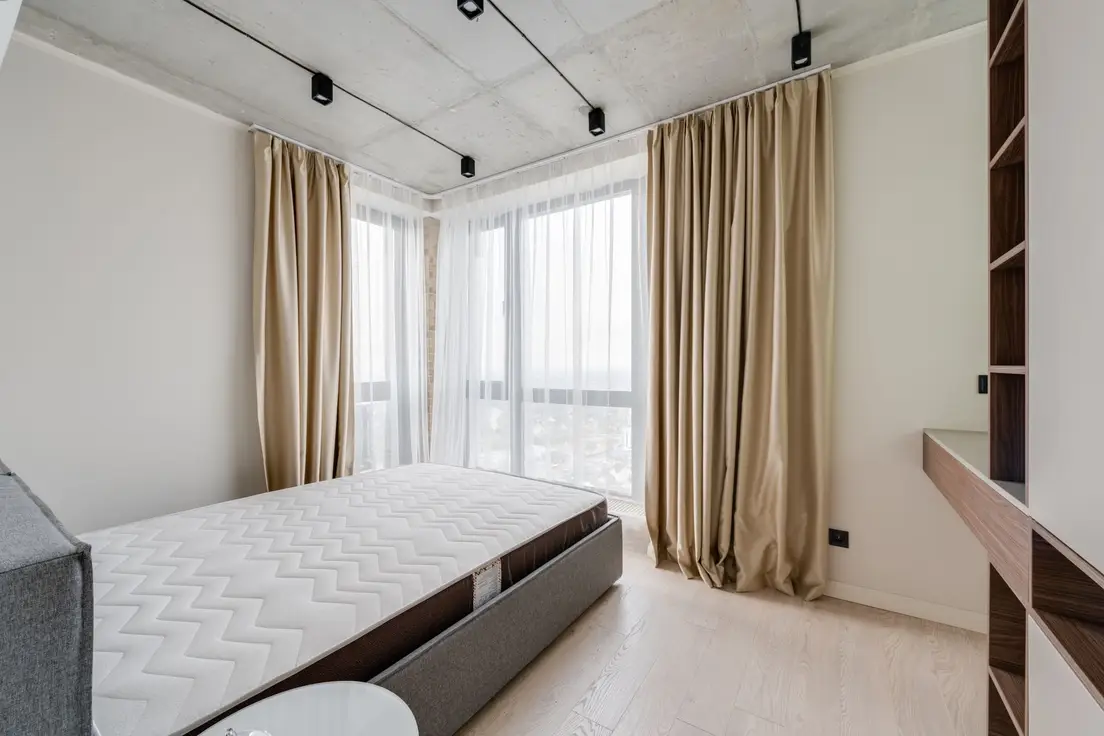 Floor-to-ceiling drapery panels in a small bedroom with a large window