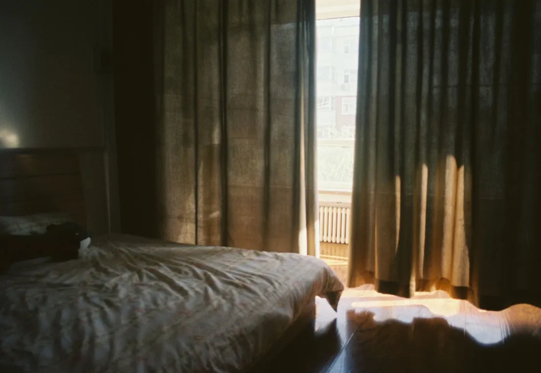 Warm afternoon light filtering through floor-length curtains in a bedroom