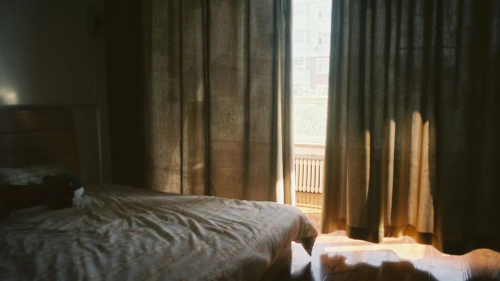Warm afternoon light filtering through floor-length curtains in a bedroom