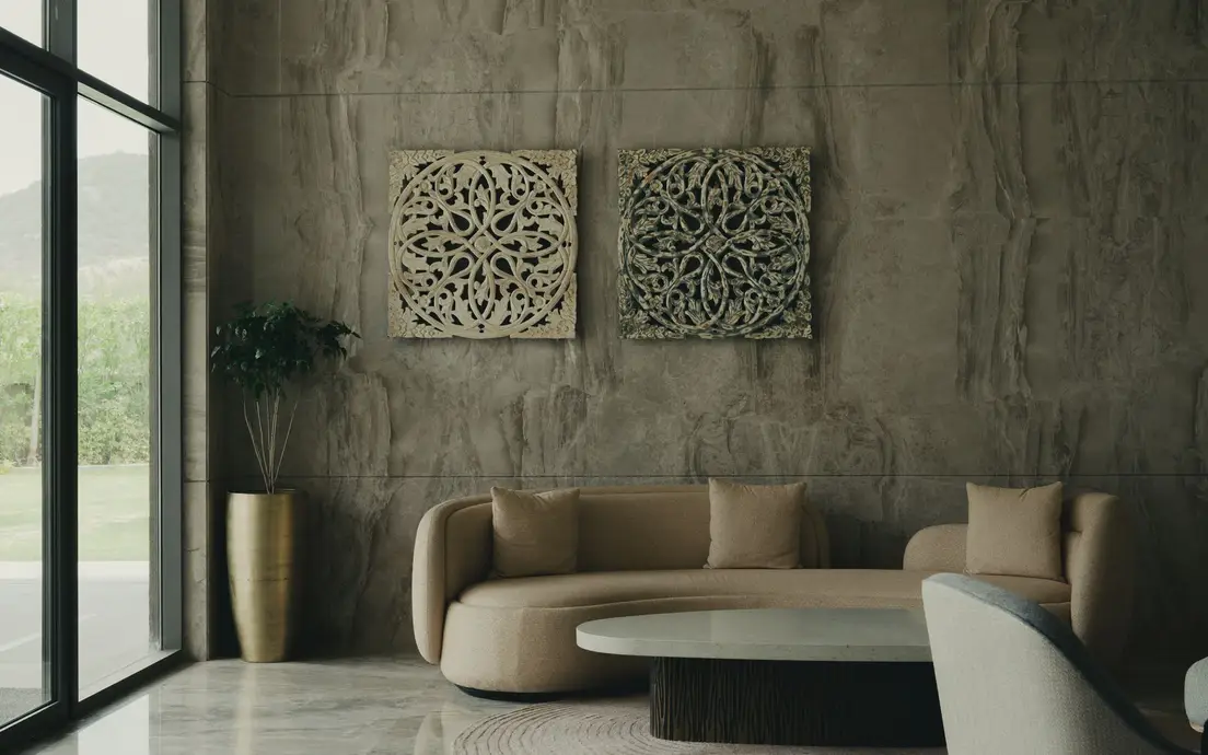A curved organic modern sofa in oatmeal fabric against a natural stone wall with a potted plant