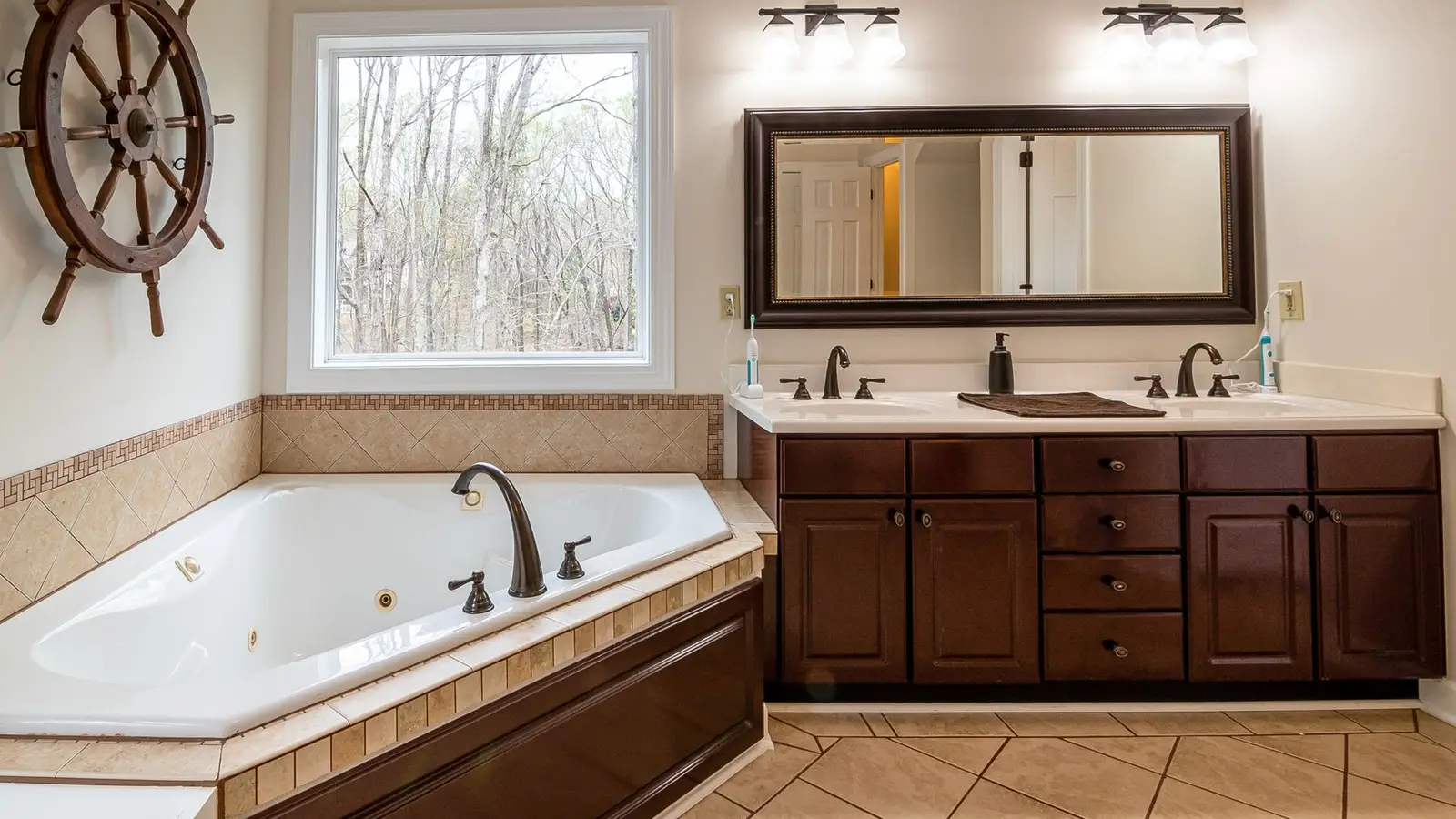 A dated bathroom vanity with a double-bulb light bar fixture above the mirror
