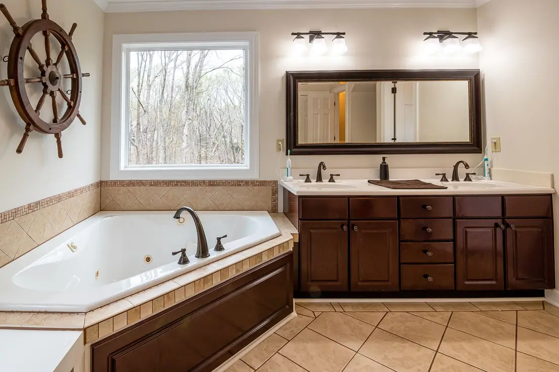 A dated bathroom vanity with a double-bulb light bar fixture above the mirror