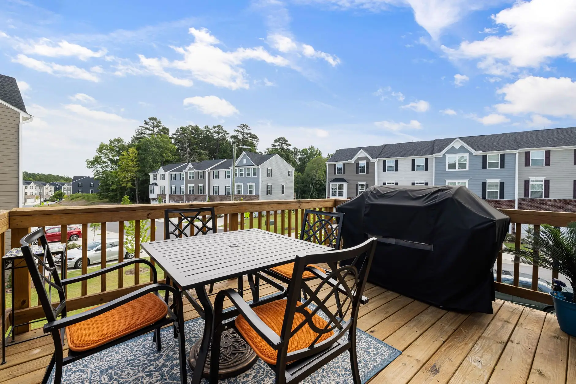 A suburban wooden deck with a table, chairs, and grill replacing backyard lawn