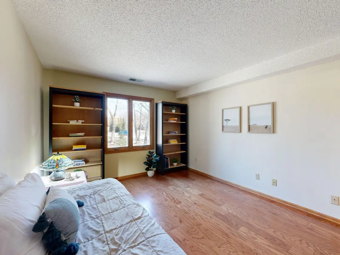 A tidy, uncluttered small bedroom with a built-in bookshelf and framed art
