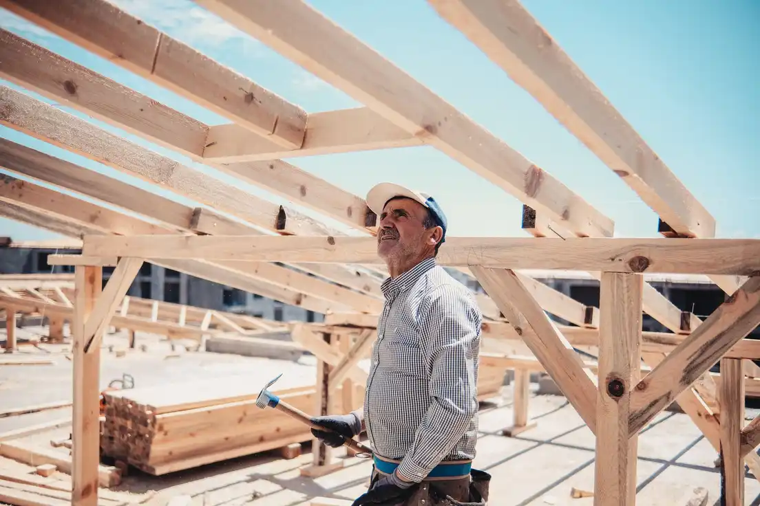 A builder checking the wood roof framing of a patio cover structure under construction