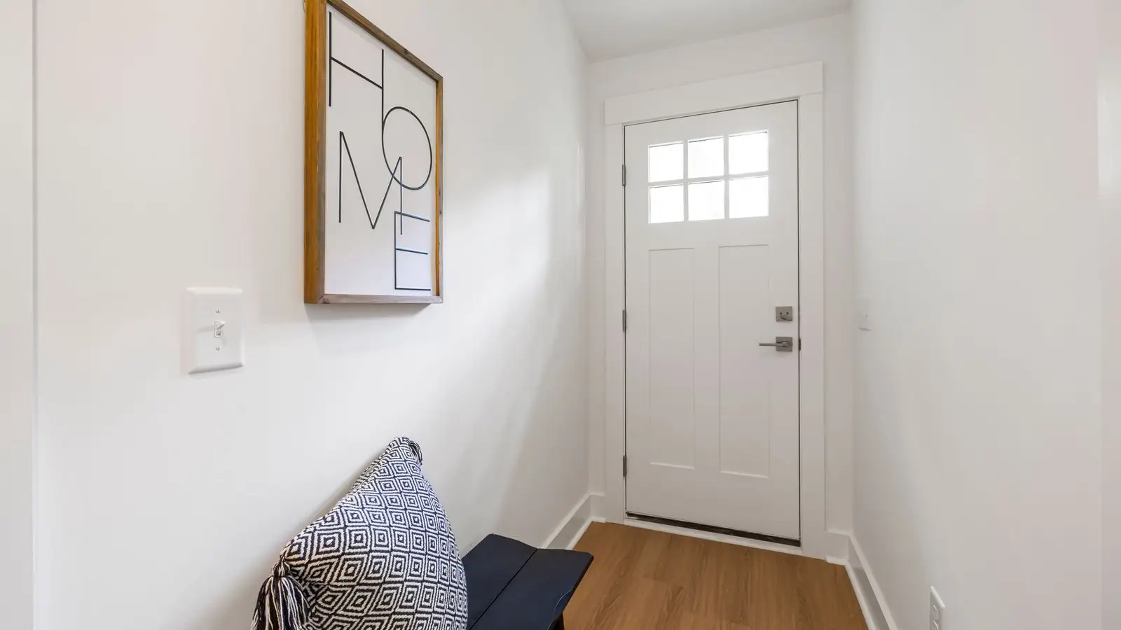 A white interior door at the end of a hallway, illustrating a door insert option for a temporary wall
