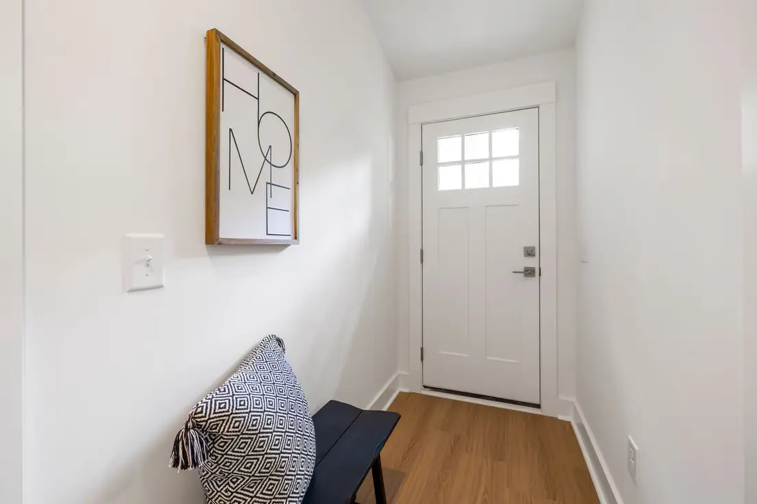 A white interior door at the end of a hallway, illustrating a door insert option for a temporary wall