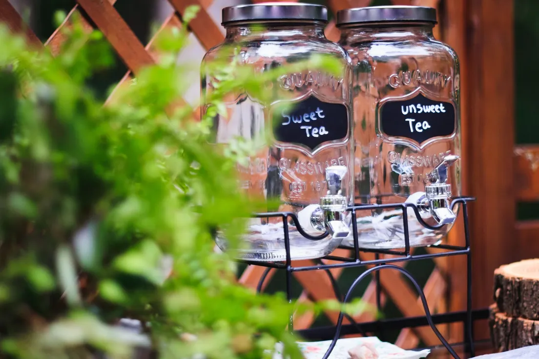 Two labeled drink dispensers on a rustic outdoor drink station