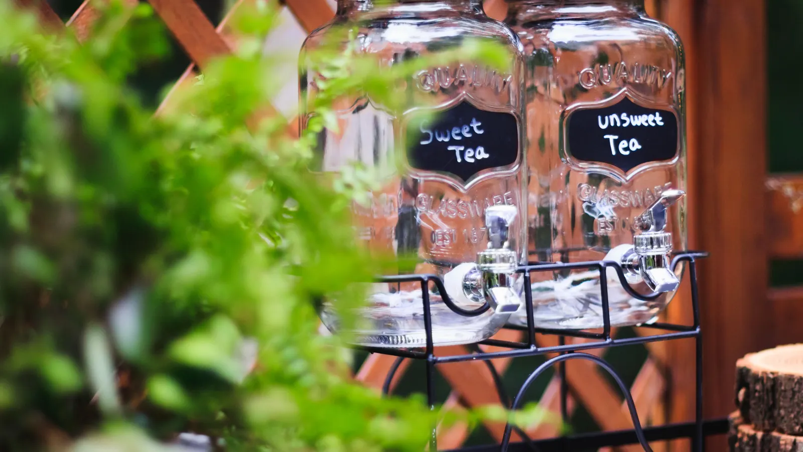Two labeled drink dispensers on a rustic outdoor drink station