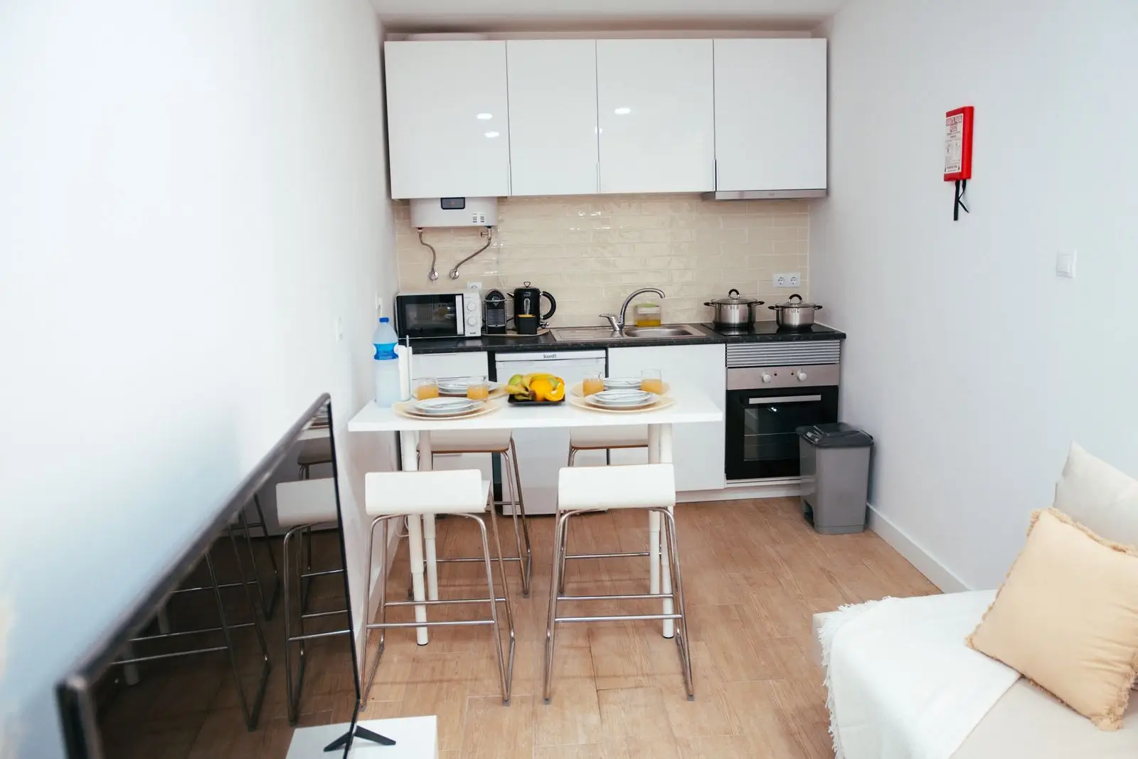 A narrow counter-height table with stools in a small apartment kitchen, doubling as prep space and a dining spot