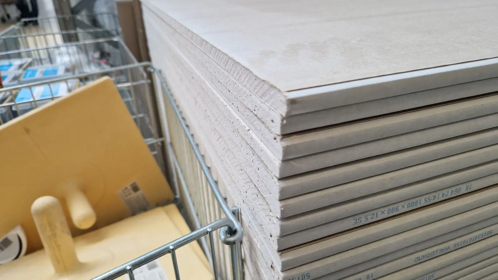 A stack of drywall sheets at a hardware store, the material for a DIY partition wall