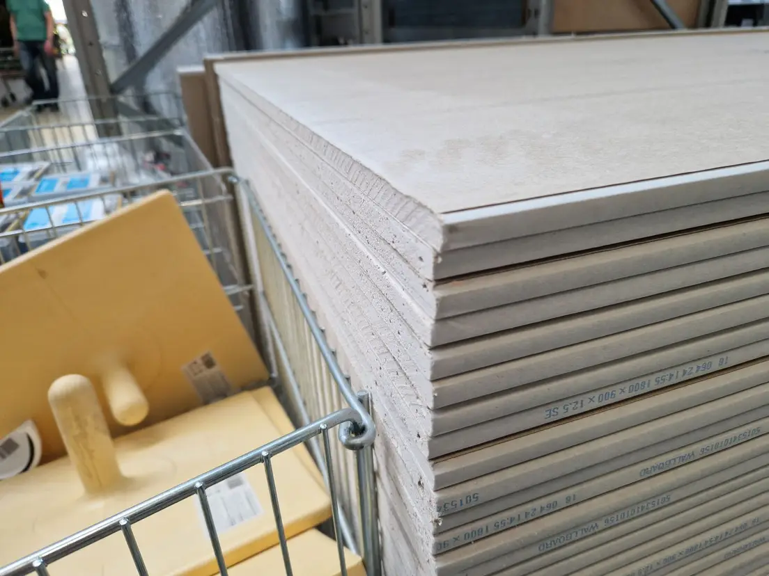 A stack of drywall sheets at a hardware store, the material for a DIY partition wall