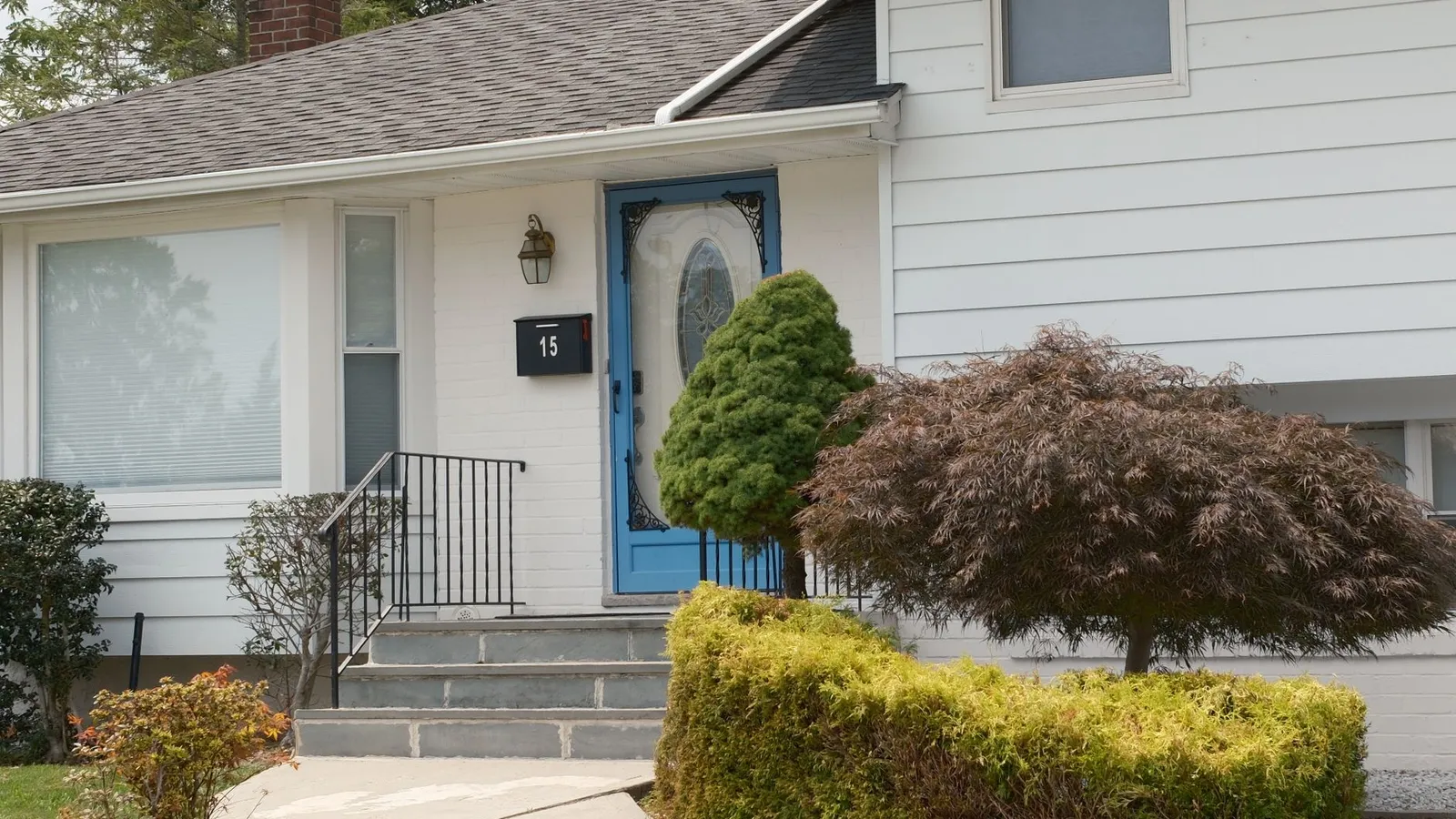 A white house with a saturated blue front door and consistent brick chimney accent