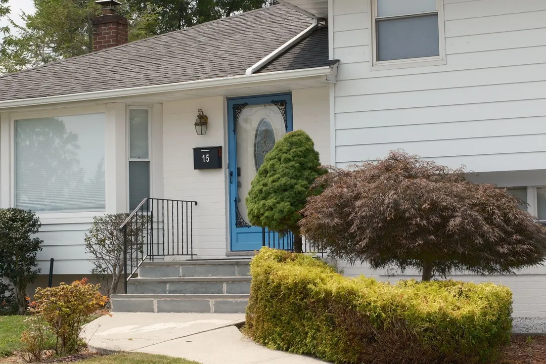 A white house with a saturated blue front door and consistent brick chimney accent