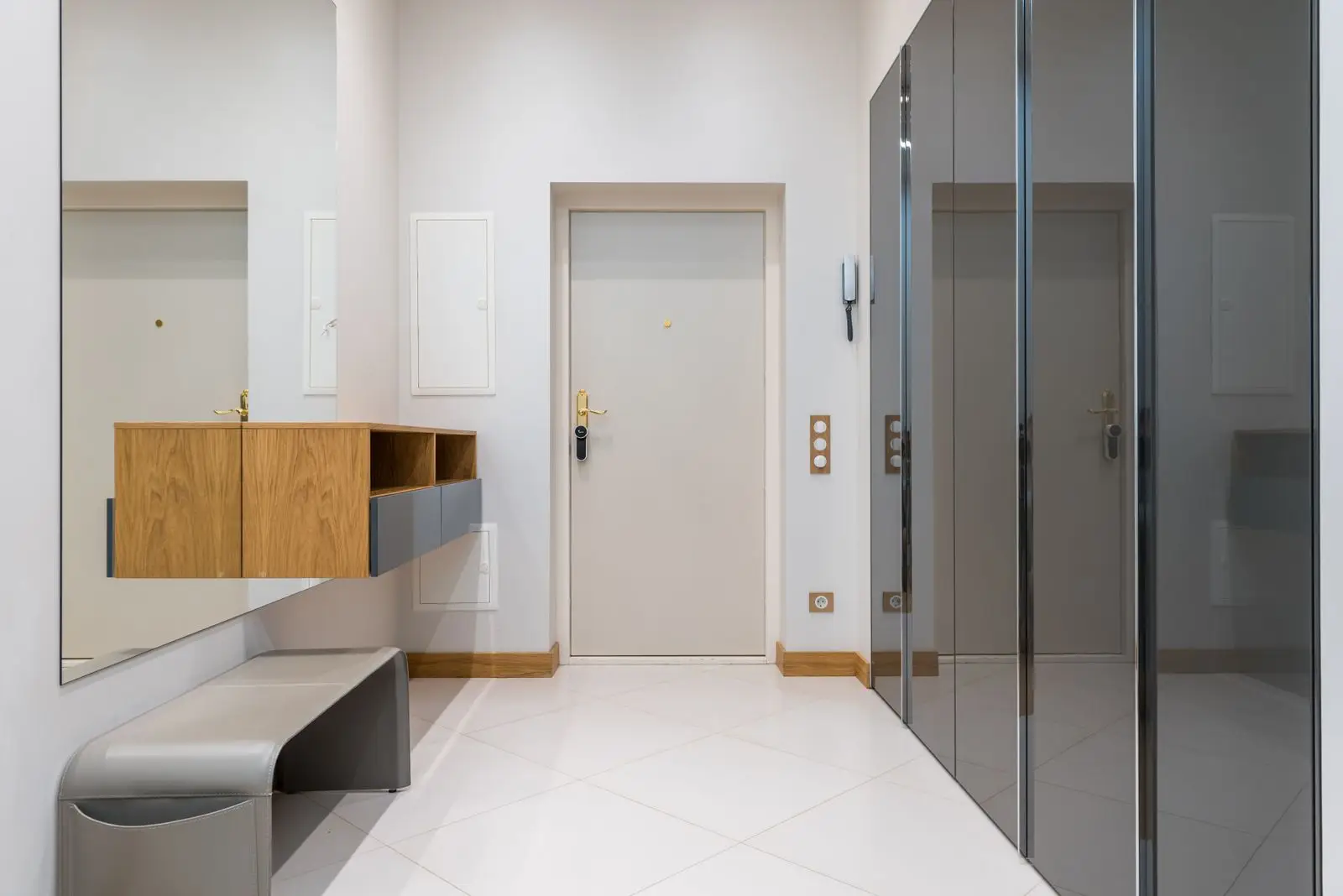 A slim bench with a floating storage cabinet above it in a small apartment entryway, a multifunctional furniture piece for a narrow hall