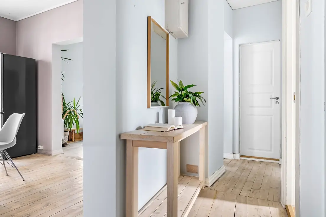 A narrow wood console table with a mirror above it in a small apartment entryway