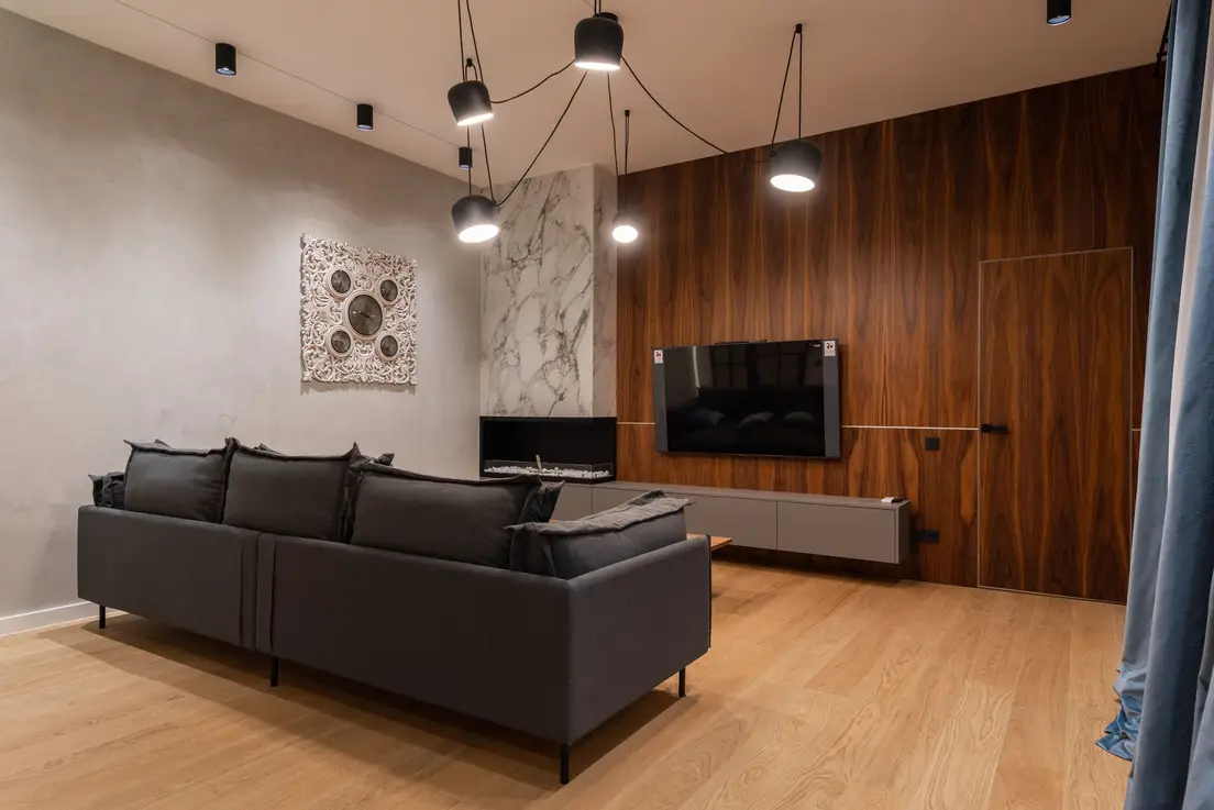 A wood-paneled TV wall beside a dark sofa in a compact living room