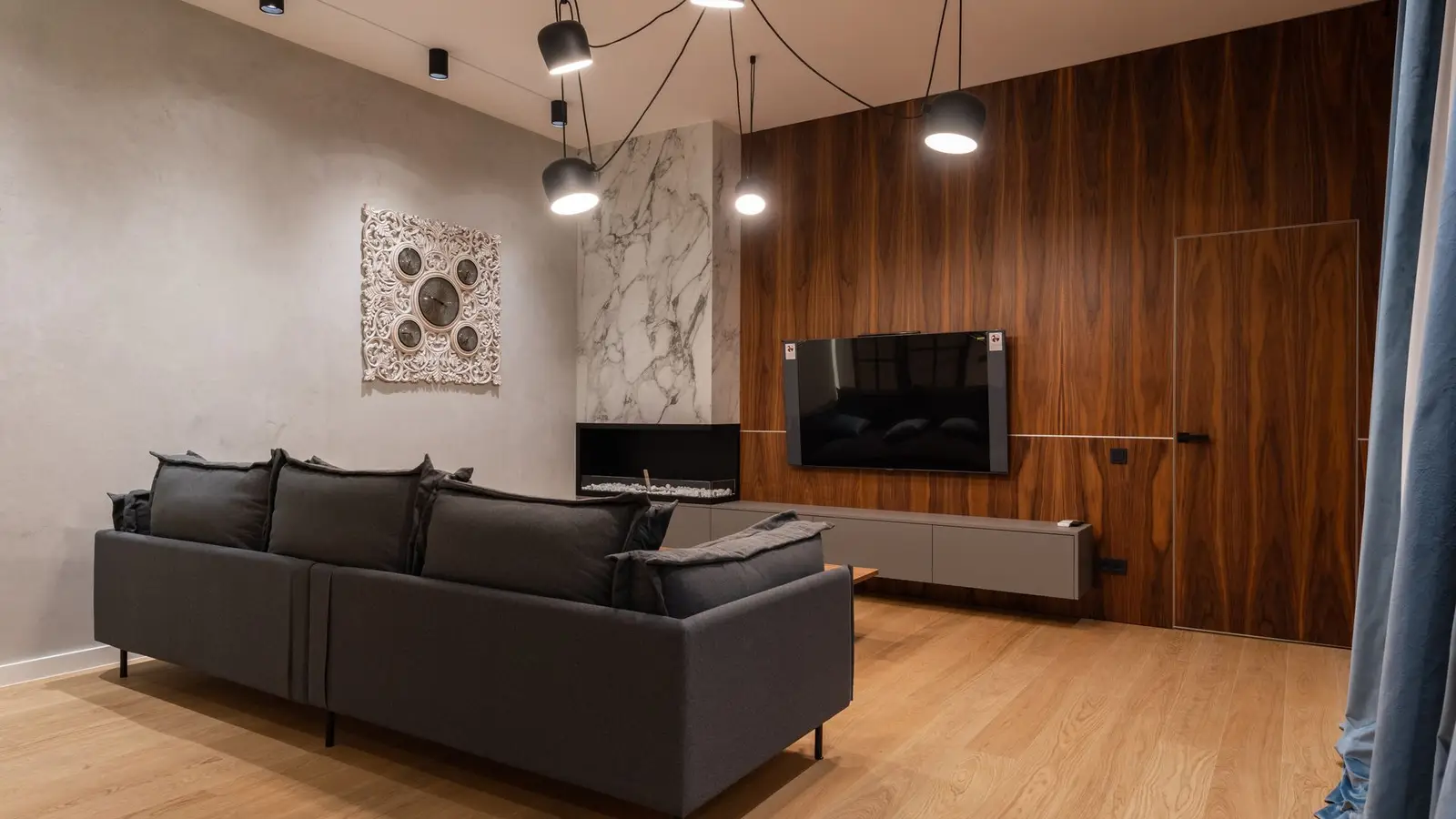 A wood-paneled TV wall beside a dark sofa in a compact living room