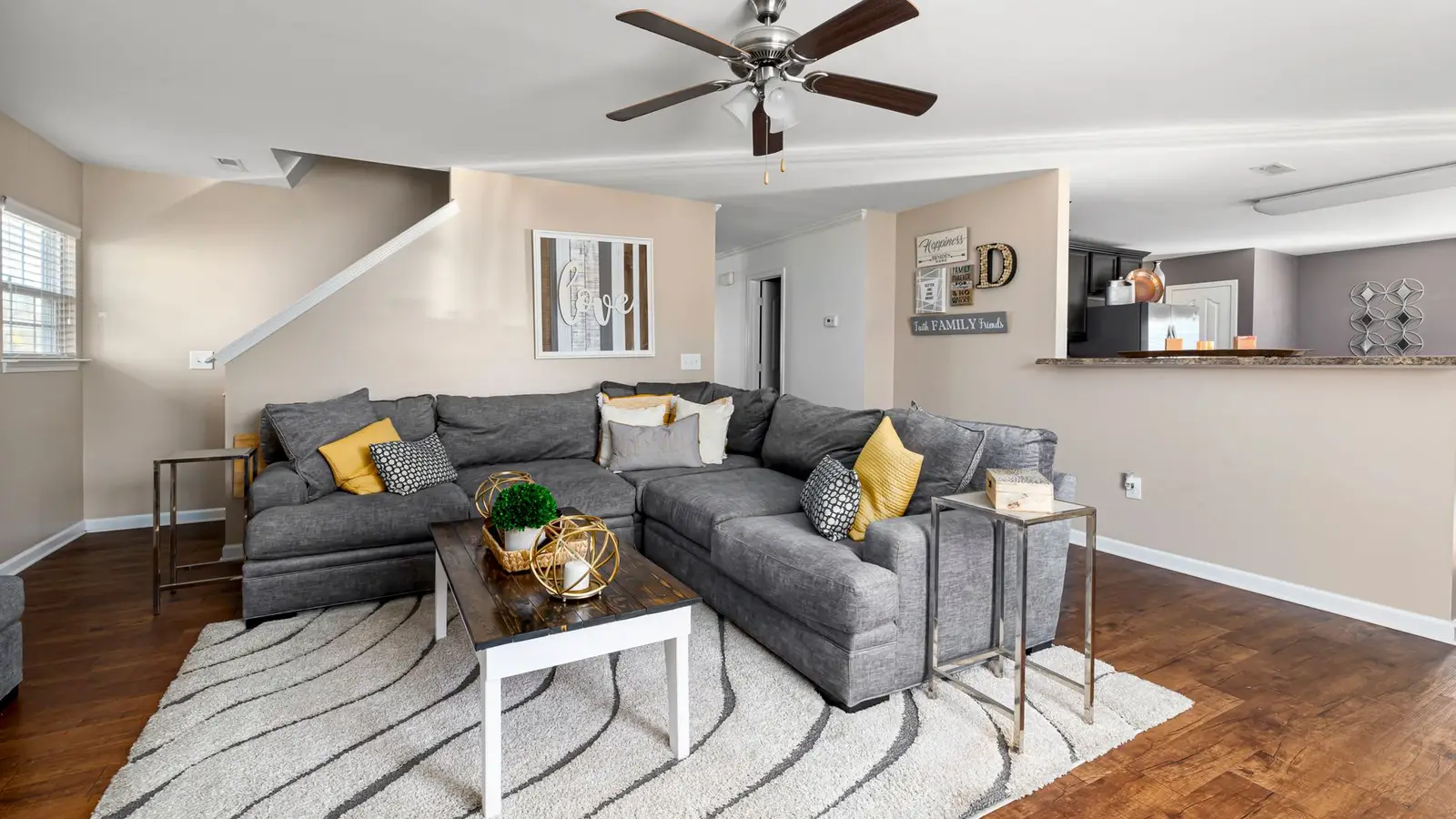 A gray sectional sofa floated a few inches off the wall in an open small living room
