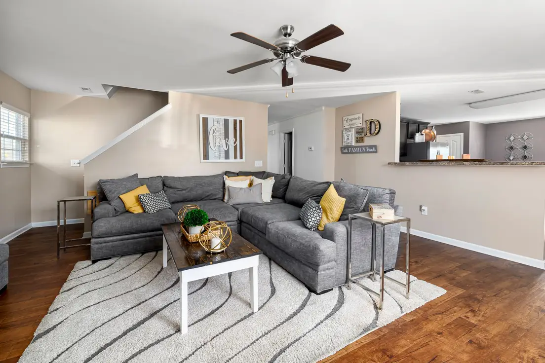 A gray sectional sofa floated a few inches off the wall in an open small living room
