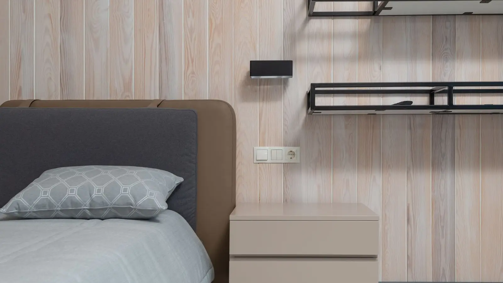 A floating wall shelf and a slim nightstand beside a bed in a small bedroom