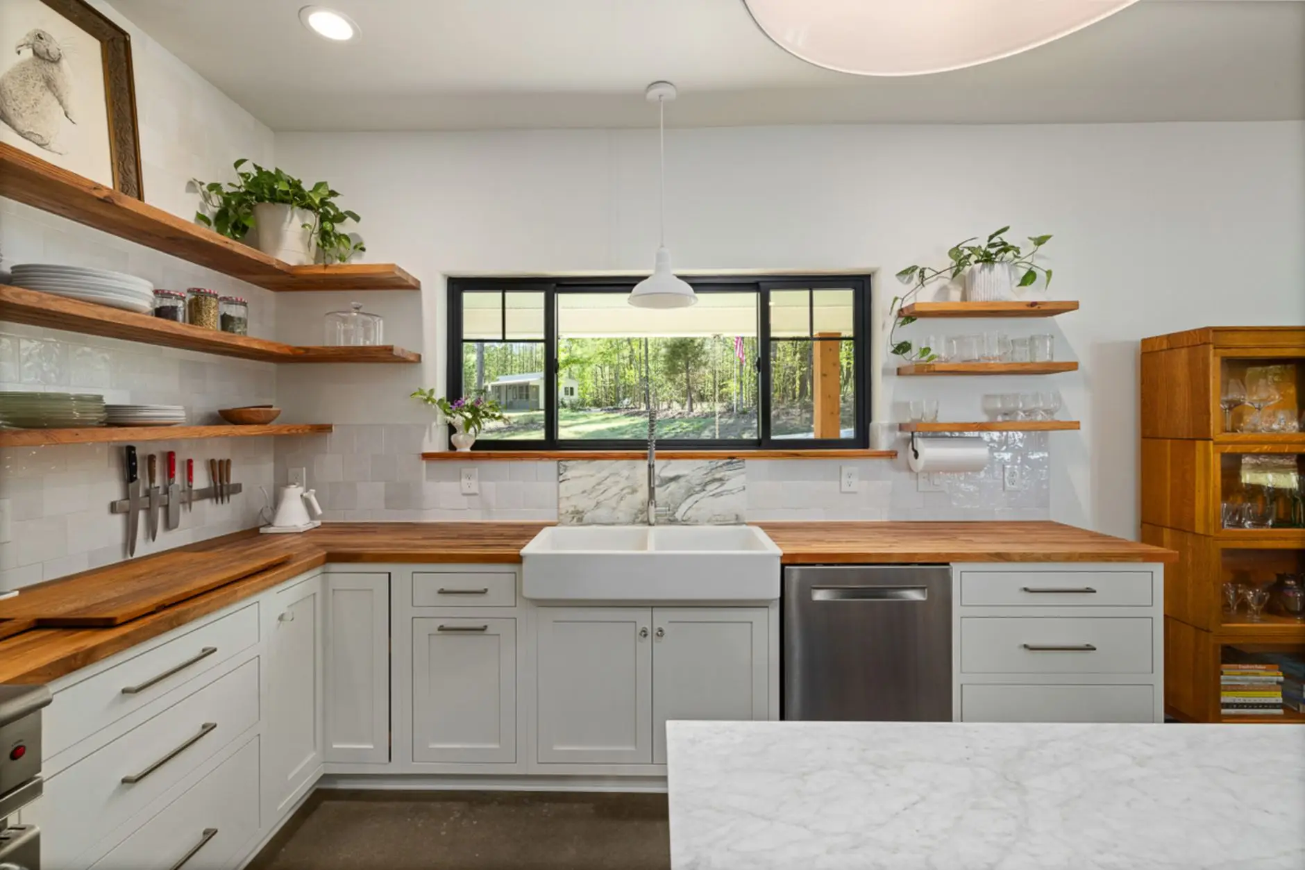 Wood floating shelves styled with dishware above a farmhouse kitchen countertop