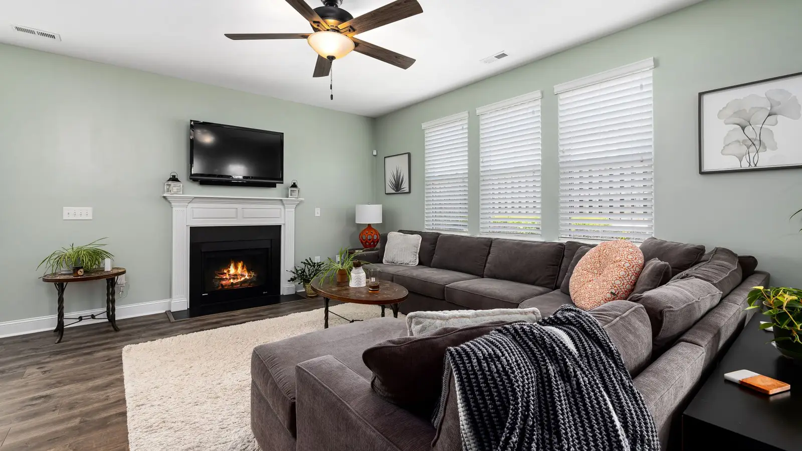 A gray sectional sofa facing a fireplace and mounted TV as the room's focal point