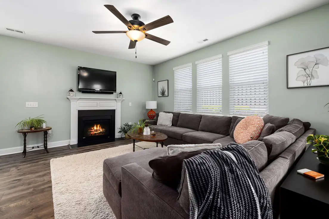 A gray sectional sofa facing a fireplace and mounted TV as the room's focal point