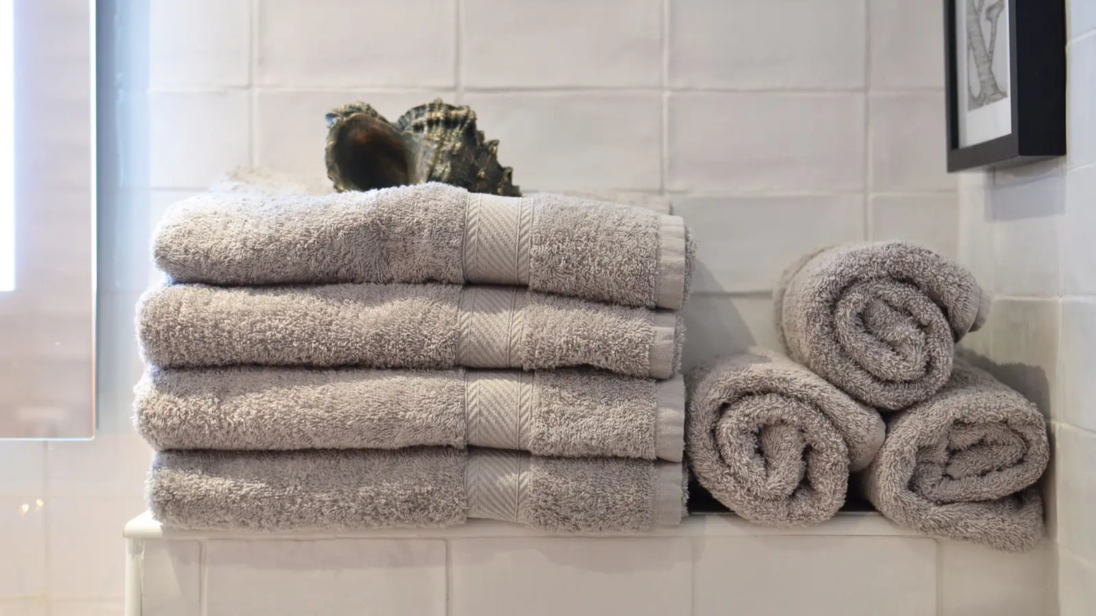 Folded bathroom towels stacked on a small tiled shelf