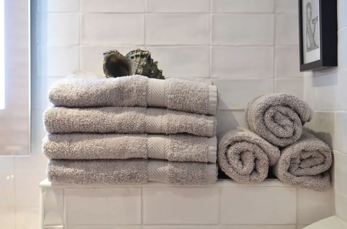Folded bathroom towels stacked on a small tiled shelf
