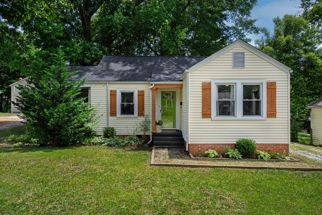 A yellow house exterior with a single repeated shrub shape along the foundation planting bed