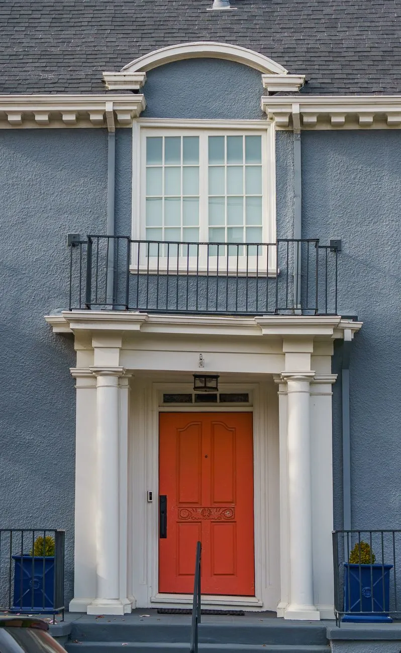 A house entrance with a vibrant red front door and white trim