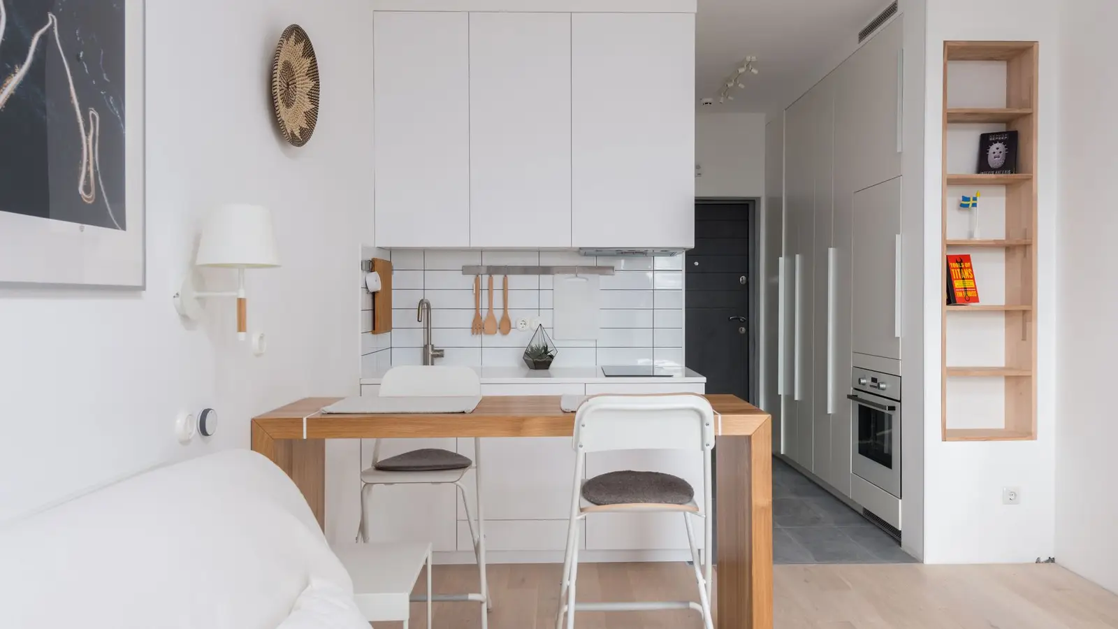 A one-wall galley kitchen with white cabinetry keeping the rest of a small apartment's floor plan open