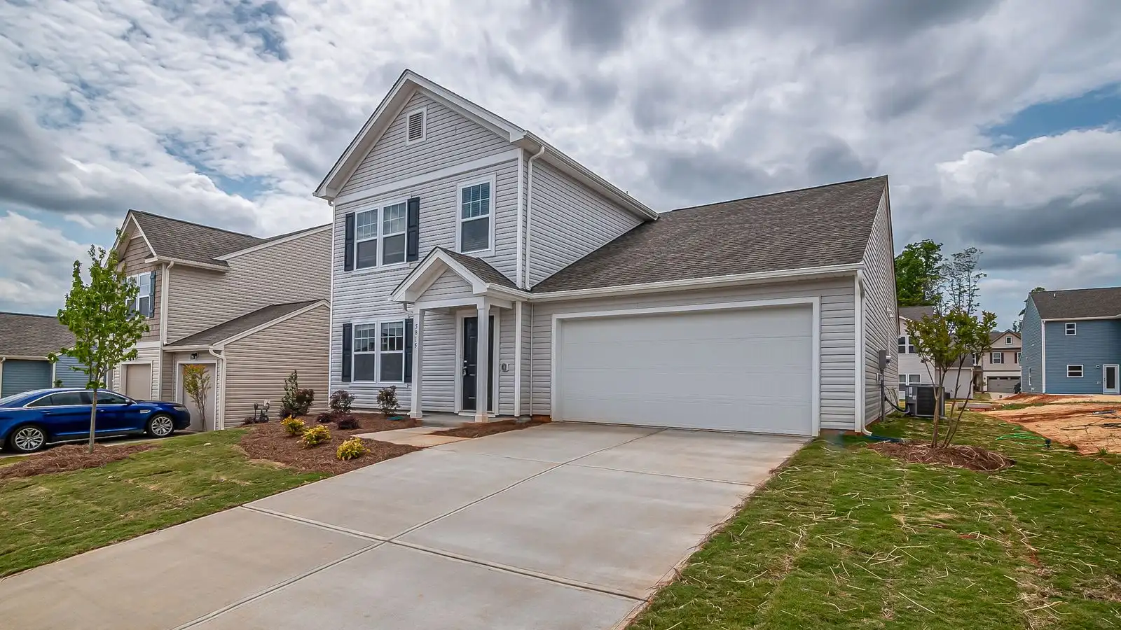 A builder-grade suburban house with a white two-car garage door facing the street